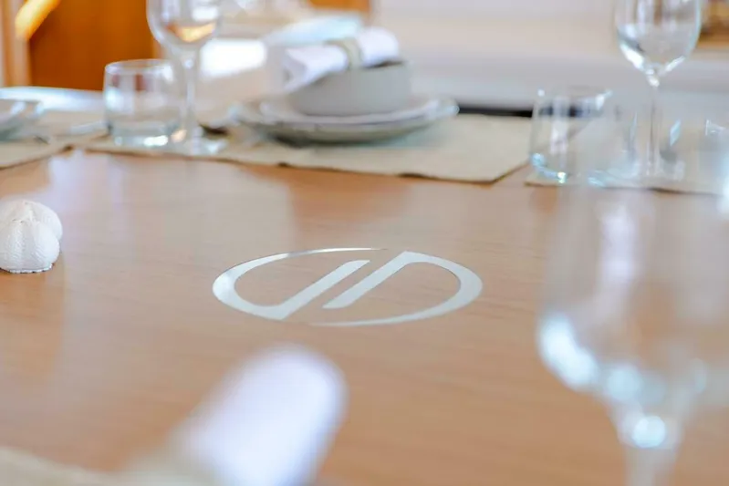 62 Iliad 2026 Yacht Photos Pics Elegant dining table setup on ILIAD 62 yacht, featuring logo and stylish tableware, 2026 model.