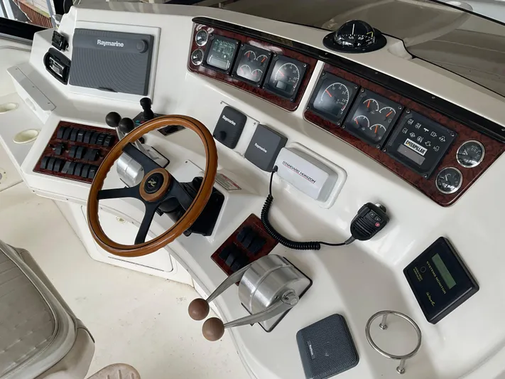  Yacht Photos Pics 1999 Sea Ray 560 Sedan Bridge helm with gauges, controls, and wooden steering wheel.