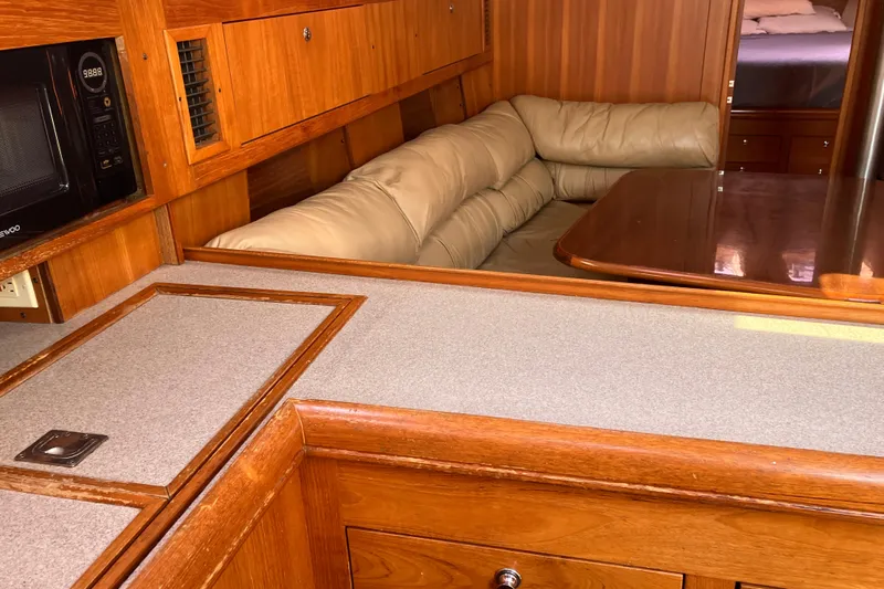 Willoughby Yacht Photos Pics Interior of 2002 Hunter 460 yacht with wood cabinetry and beige seating area.