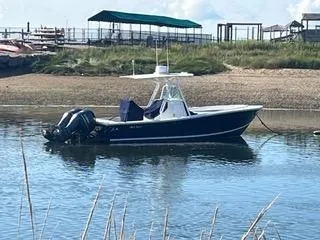  Yacht Photos Pics 2013 Regulator 26 FS boat anchored in calm waters near a sandy shore.