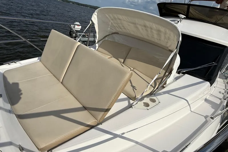 Tomtanic Yacht Photos Pics 2019 Regal 42 Fly yacht with beige seating on deck, overlooking water.