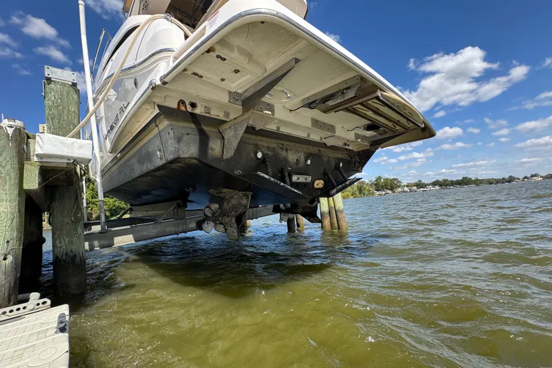 Tomtanic Yacht Photos Pics 2019 Regal 42 Fly yacht on lift, showcasing hull and propeller, against a scenic waterfront.