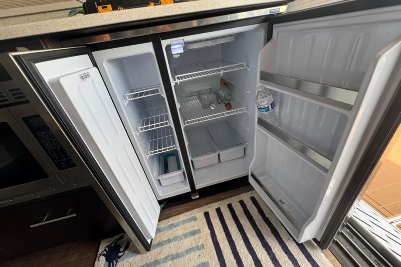 Tomtanic Yacht Photos Pics Open refrigerator on a 2019 Regal 42 Fly yacht, showing shelves and bottled water.