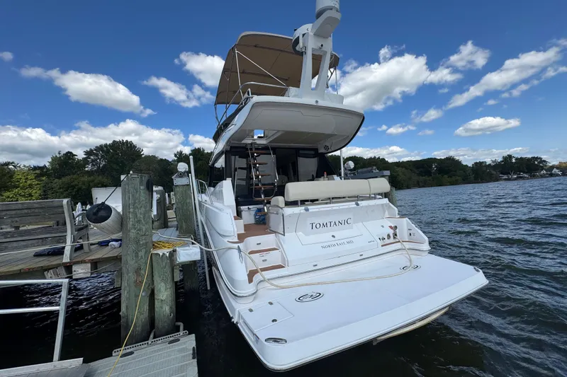Tomtanic Yacht Photos Pics 2019 Regal 42 Fly yacht docked by a scenic waterfront under a blue sky.
