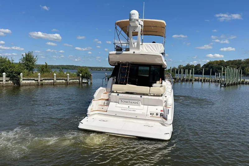 Tomtanic Yacht Photos Pics 2019 Regal 42 Fly yacht cruising on a sunny day near a dock.
