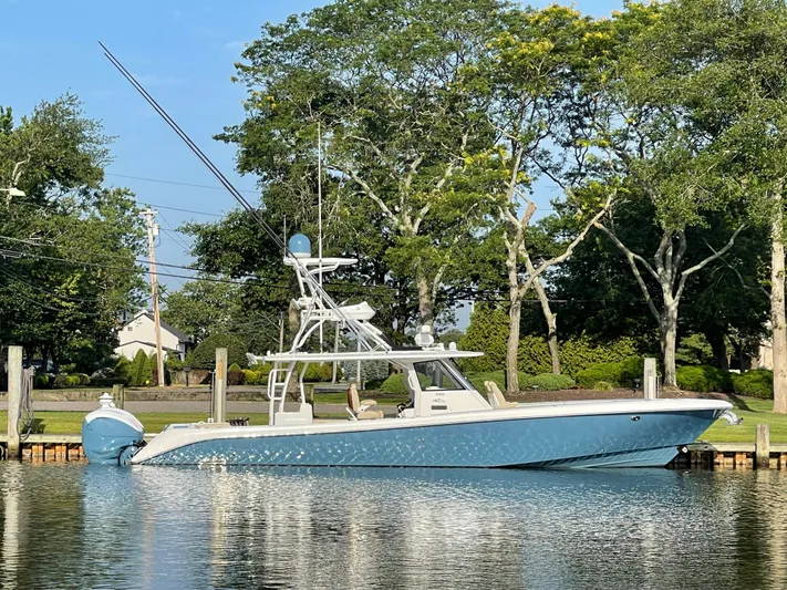  Yacht Photos Pics 2019 Everglades 435 CC boat docked on a calm lake with trees in the background.