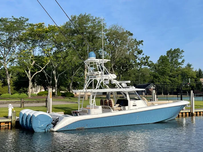  Yacht Photos Pics 2019 Everglades 435 CC boat docked on a calm waterway, surrounded by lush greenery.