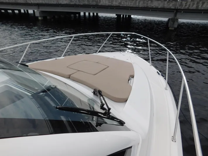  Yacht Photos Pics 2018 Pursuit OS 325 Offshore boat with cushioned deck, docked near a bridge.