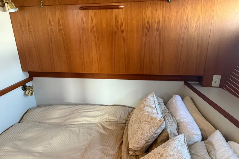  Yacht Photos Pics Cozy bedroom in 1998 Kadey-Krogen 48' Northsea Widebody Pilothouse with wood paneling and elegant bedding.