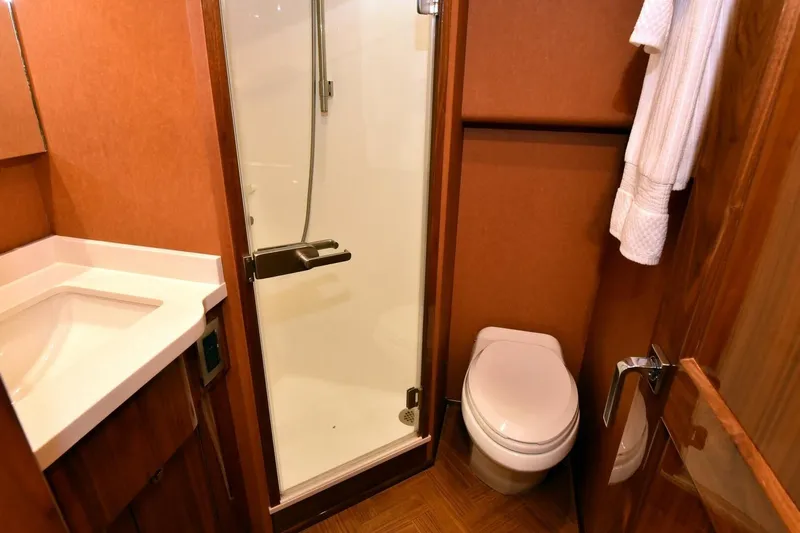 Party Of Five Yacht Photos Pics Bathroom interior of 2019 Viking 80 Sky Bridge yacht, featuring shower, toilet, and sink.