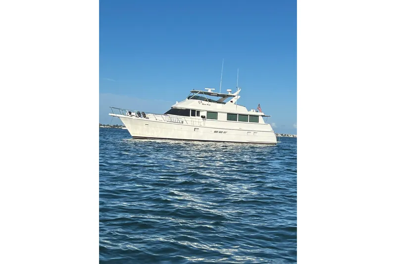 Moon River Yacht Photos Pics 1997 Hatteras 70 Sport Deck Motor Yacht on calm blue water under clear sky.