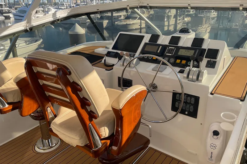 Moon River Yacht Photos Pics Helm of 1997 Hatteras 70 Sport Deck Motor Yacht with wooden chairs and control panel.