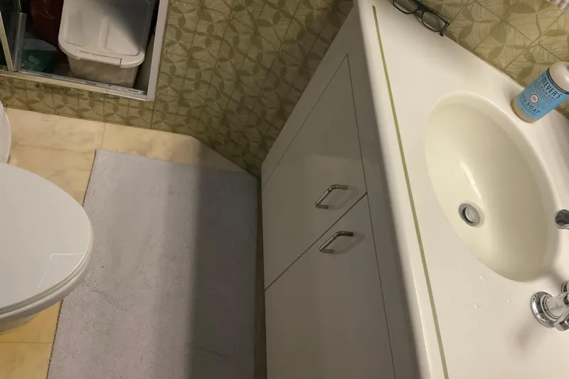 Moon River Yacht Photos Pics Bathroom interior of 1997 Hatteras 70 Sport Deck Motor Yacht, featuring sink and storage.