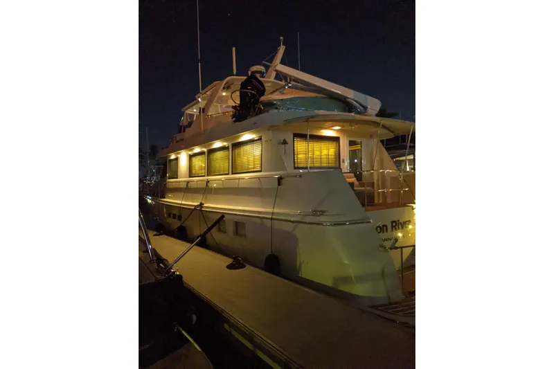 Moon River Yacht Photos Pics 1997 Hatteras 70 Sport Deck Motor Yacht docked at night, illuminated by soft lighting.
