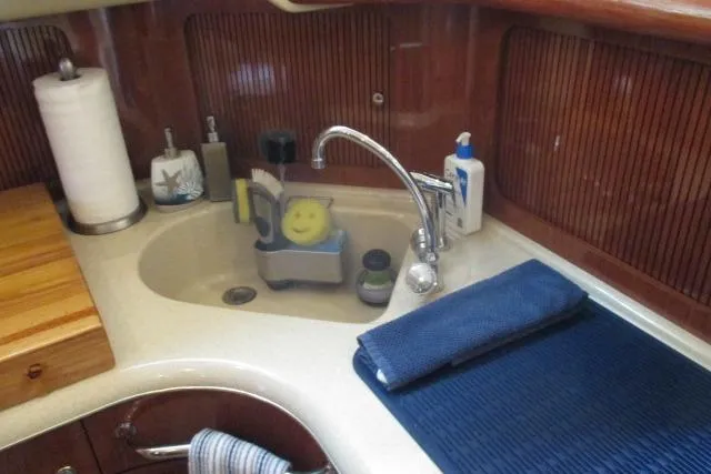 Pho-king-gross Yacht Photos Pics 2002 Sea Ray 400 Sedan Bridge bathroom sink with toiletries and wooden accents.