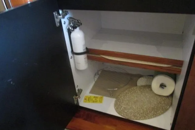 Pho-king-gross Yacht Photos Pics Open cabinet on 2002 Sea Ray 400 Sedan Bridge with fire extinguisher and storage items.