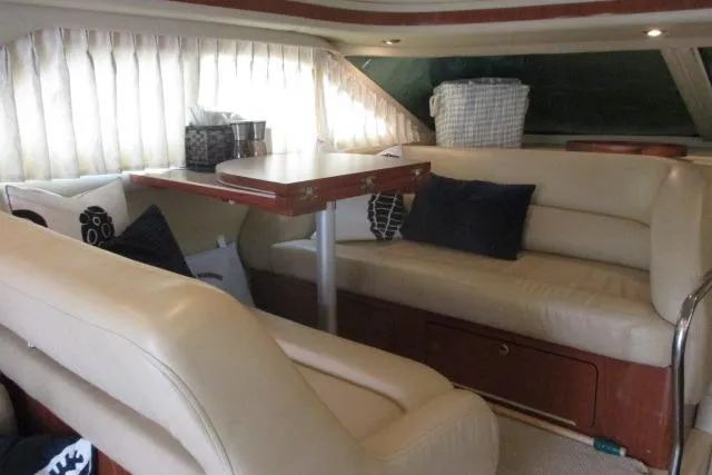 Pho-king-gross Yacht Photos Pics Interior of 2002 Sea Ray 400 Sedan Bridge with cream leather seating and wooden table.