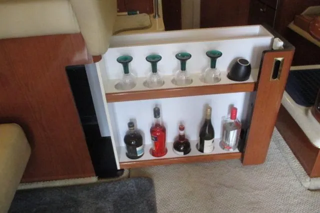 Pho-king-gross Yacht Photos Pics Bar area inside a 2002 Sea Ray 400 Sedan Bridge yacht with glasses and liquor bottles.