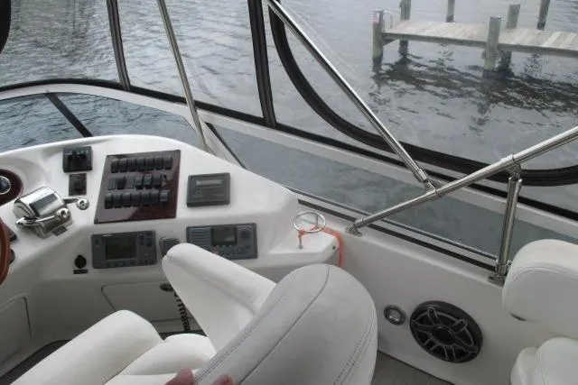 Pho-king-gross Yacht Photos Pics Cockpit view of 2002 Sea Ray 400 Sedan Bridge yacht with control panel and water backdrop.