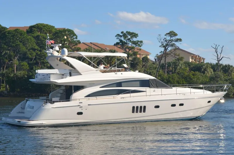  Yacht Photos Pics 2006 Princess 67 Flybridge yacht cruising on a sunny day near lush greenery.