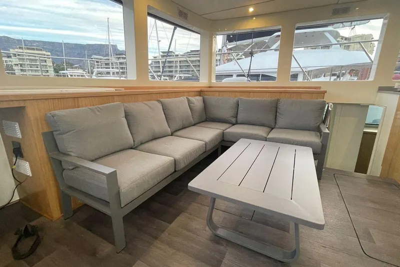 Pilar X Yacht Photos Pics Modern interior of 2024 Leeuwin 55 yacht with gray sectional sofa and sleek table.