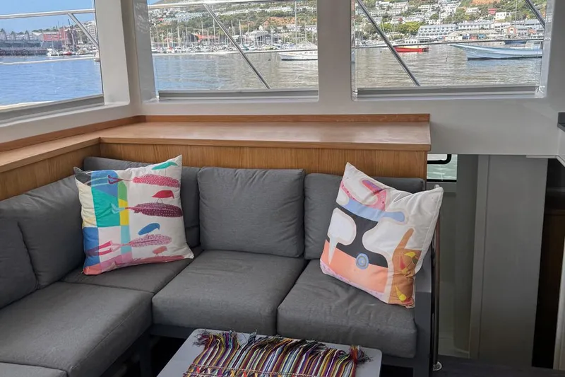 Pilar X Yacht Photos Pics Interior of Leeuwin 55 yacht, 2024, featuring gray sofa and colorful pillows.