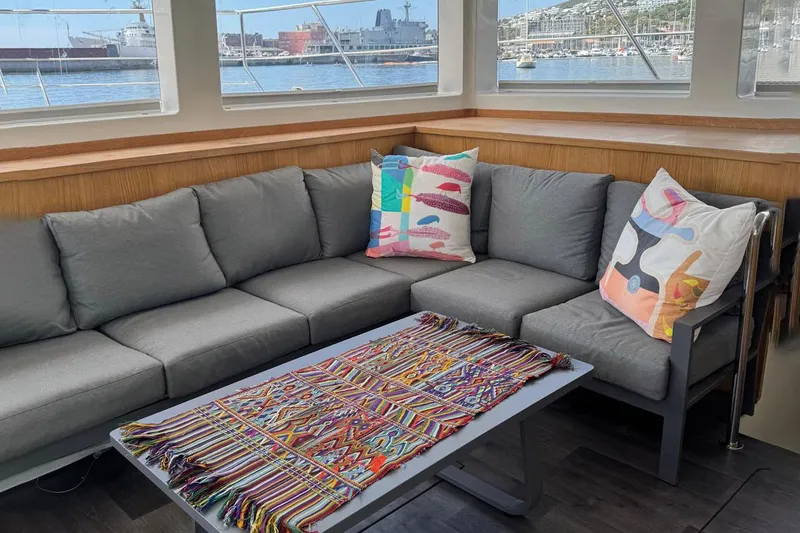 Pilar X Yacht Photos Pics Interior of Leeuwin 55 yacht, 2024, featuring gray sofa and colorful pillows.