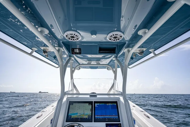 34 Offshore Yacht Photos Pics 2025 Yellowfin 34 Offshore boat interior with navigation screens, ocean view, and blue canopy.