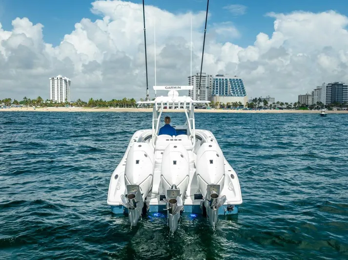 34 Offshore Yacht Photos Pics 2025 Yellowfin 34 Offshore boat with triple engines on open water near city skyline.