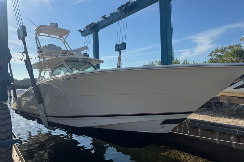  Yacht Photos Pics 2019 Scout 420 LXF boat in a marina lift under clear blue sky.