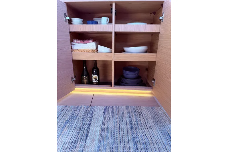 One Five Yacht Photos Pics Cabinet interior with dishes and wine bottles on Beneteau Oceanis Yacht 54, 2022 model.