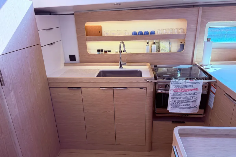 One Five Yacht Photos Pics Modern kitchen in 2022 Beneteau Oceanis Yacht 54, featuring sleek wood cabinetry and stainless steel appliances.