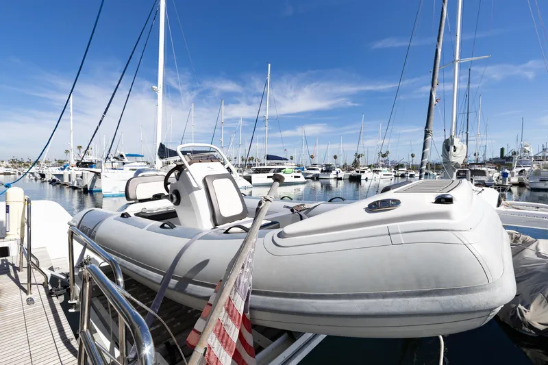 Second Wind Yacht Photos Pics Docked Lagoon 52 F yacht, 2022 model, with inflatable boat, in a marina under clear skies.