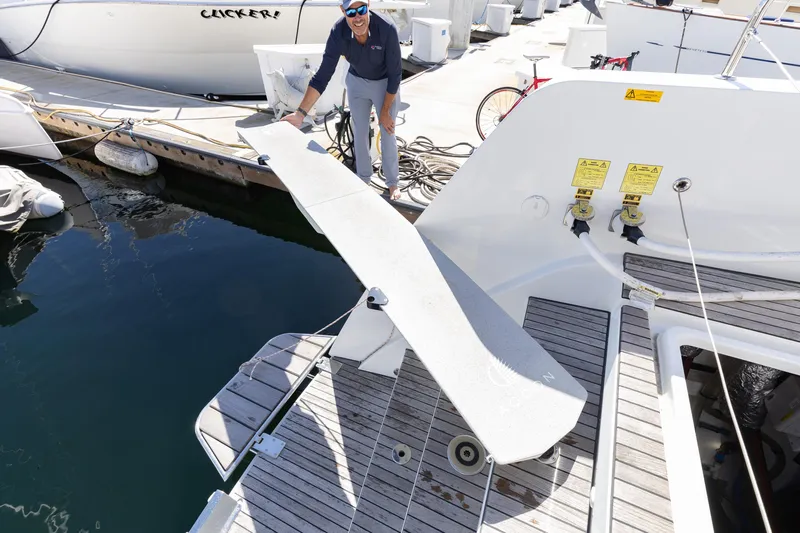 Second Wind Yacht Photos Pics Person on Lagoon 52 F yacht, 2022 model, adjusting gangway at marina.