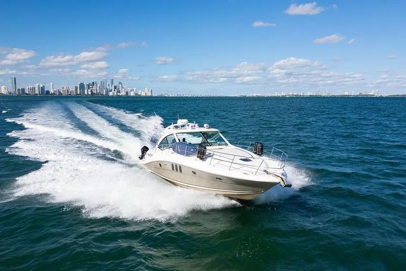  Yacht Photos Pics 2005 Sea Ray 48 Sundancer cruising on open water with city skyline in background.