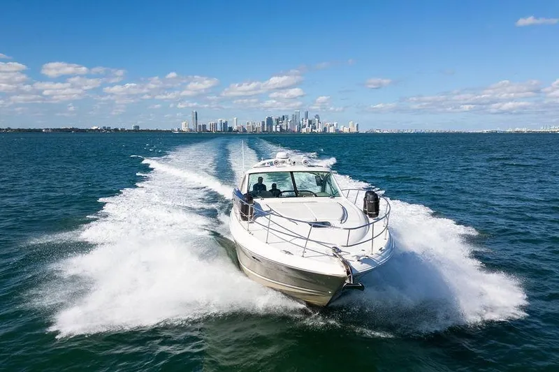  Yacht Photos Pics 2005 Sea Ray 48 Sundancer cruising on open water with city skyline backdrop.