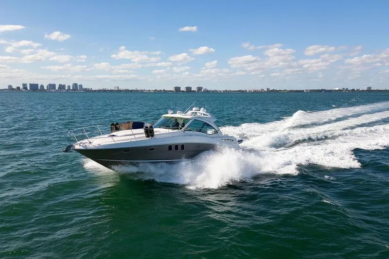  Yacht Photos Pics 2005 Sea Ray 48 Sundancer yacht cruising on open water with city skyline in background.