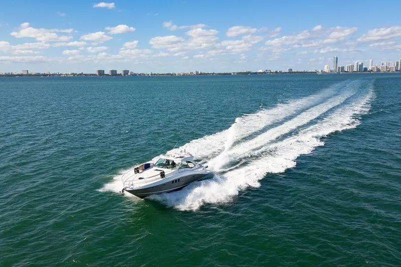  Yacht Photos Pics 2005 Sea Ray 48 Sundancer cruising on open water with city skyline in background.