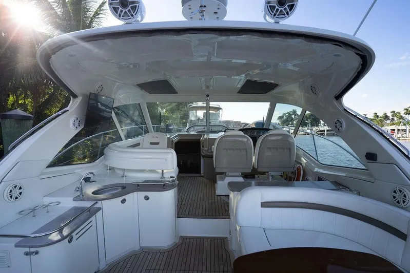  Yacht Photos Pics 2005 Sea Ray 48 Sundancer yacht interior with seating, kitchenette, and helm, docked by palm trees.