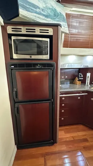 Get N Free Yacht Photos Pics 2006 Sea Ray 44 Sedan Bridge kitchen with microwave, fridge, and wooden cabinetry.