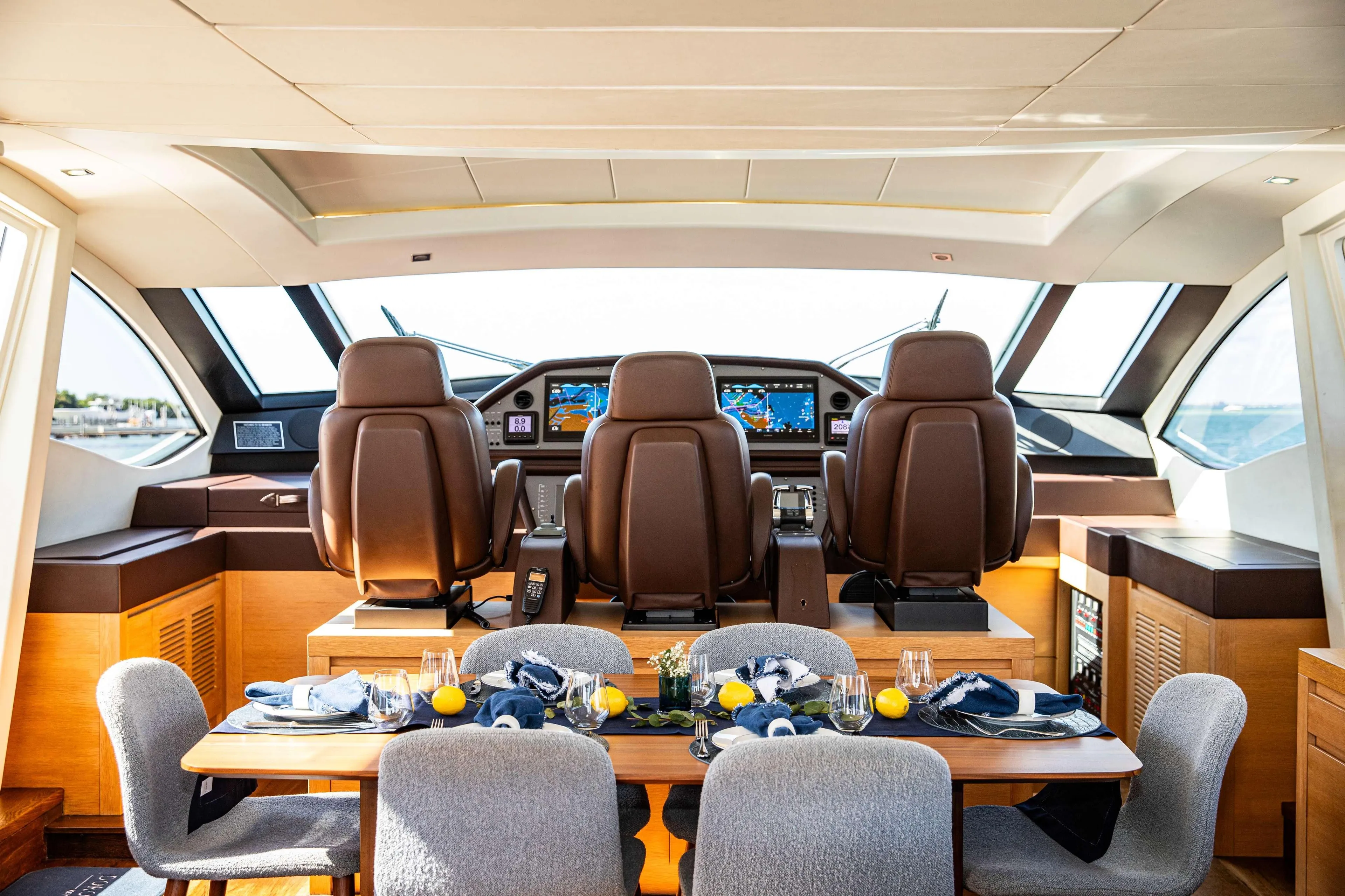 Luxurious interior of 2012 Pershing 82 yacht with elegant dining setup and modern helm.