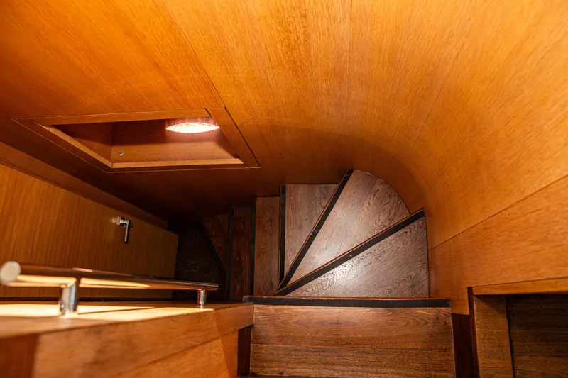 Dorothy Ann Yacht Photos Pics Wooden spiral staircase inside 2012 Pershing 82 yacht, featuring elegant design and warm lighting.