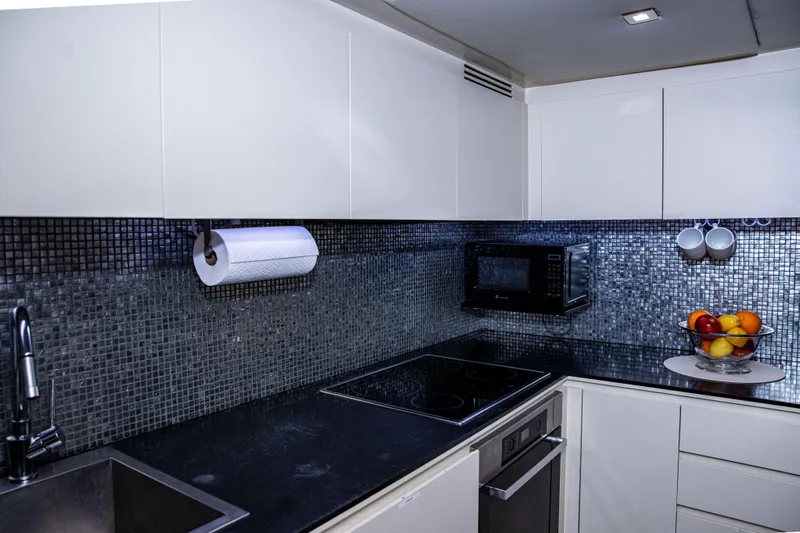 Dorothy Ann Yacht Photos Pics Modern kitchen in a 2012 Pershing 82 yacht with sleek black countertops.