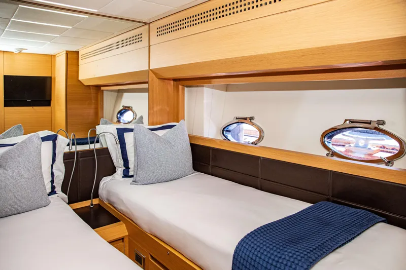 Dorothy Ann Yacht Photos Pics Luxurious twin cabin interior on 2012 Pershing 82 yacht, featuring elegant bedding and porthole windows.