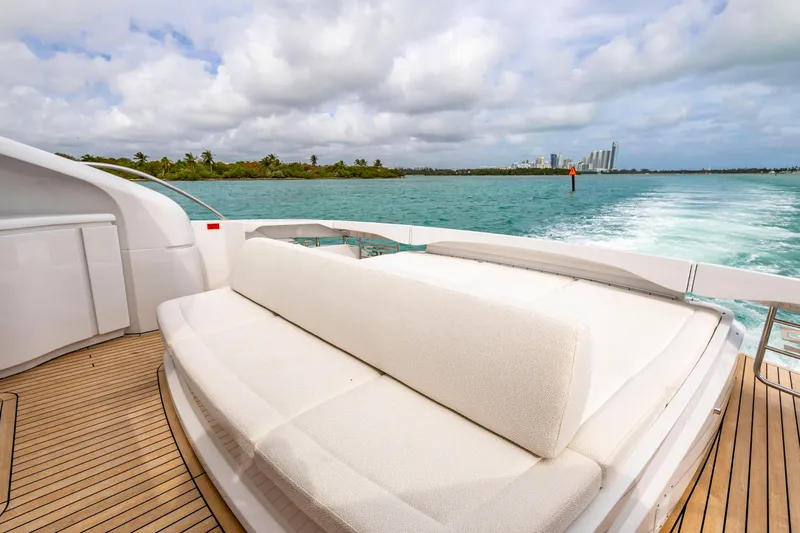 Sea Suite I Yacht Photos Pics Luxurious 2021 Pershing 62 yacht with spacious deck, cruising on turquoise waters under a cloudy sky.