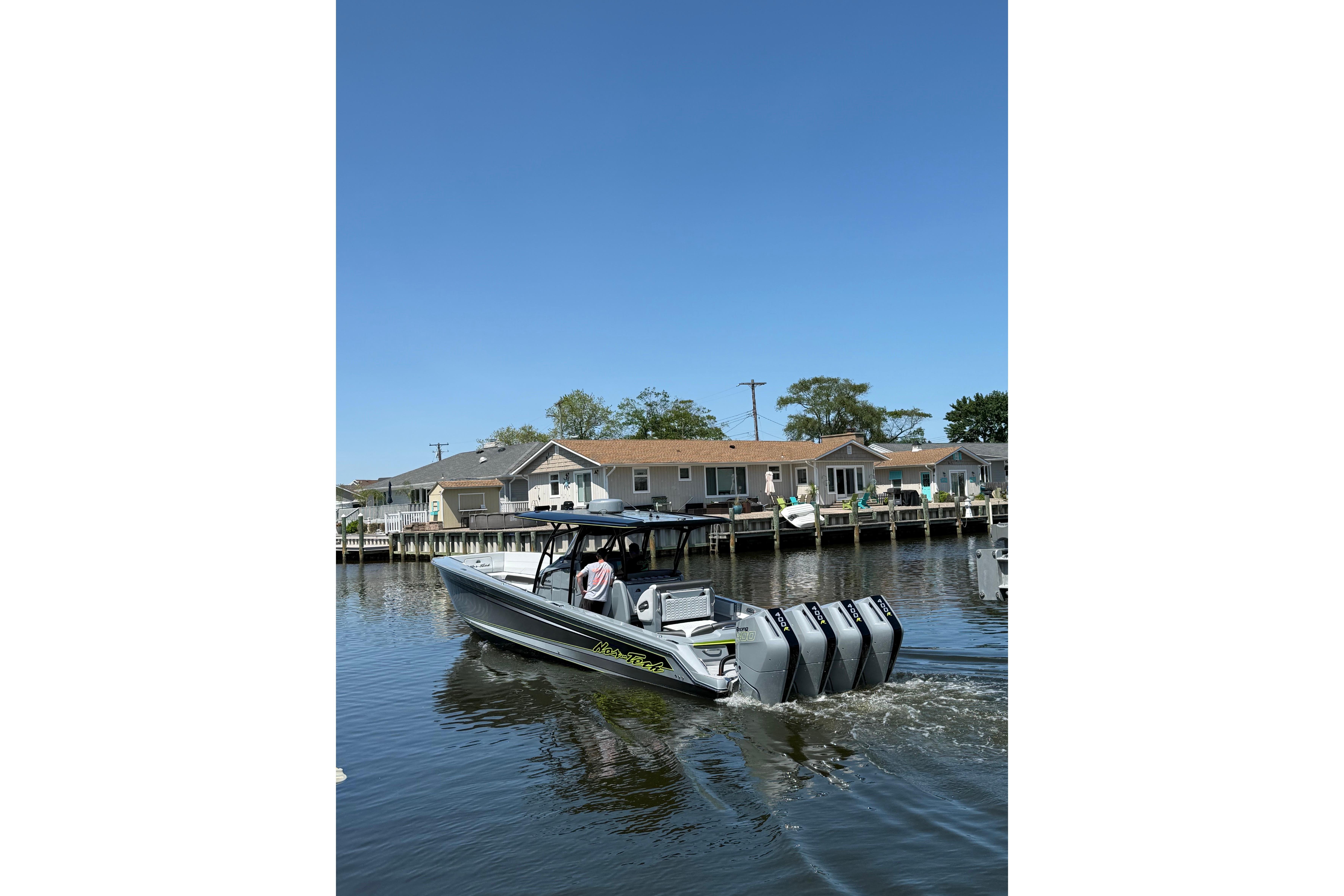 2026 Nor-Tech 390 Sport Center Console boat cruising on a sunny day near waterfront homes.