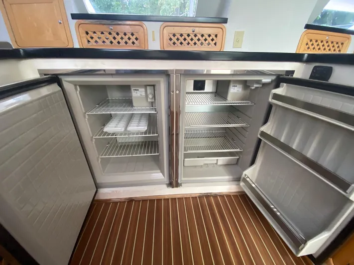 Ronin Yacht Photos Pics Open double-door fridge in 2016 Celtic Yachts 40, featuring spacious interior and wooden flooring.