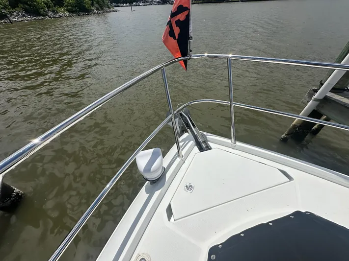 Sea Addendum Yacht Photos Pics Bow of 2021 Galeon 425 HTS yacht with railing and flag on calm water.