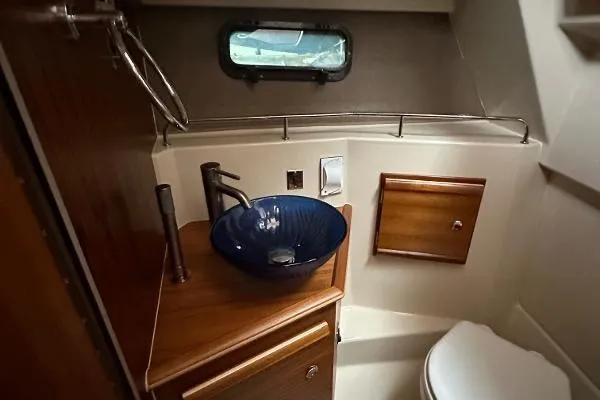  Yacht Photos Pics 2021 Ranger Tugs R-27 bathroom with modern sink, wooden cabinetry, and compact design.