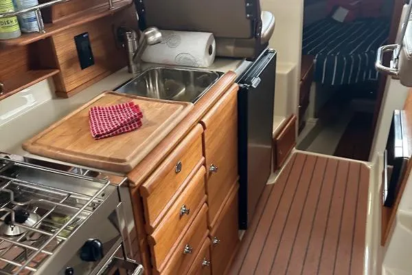 Yacht Photos Pics 2021 Ranger Tugs R-27 galley with wooden cabinetry, sink, and compact appliances.